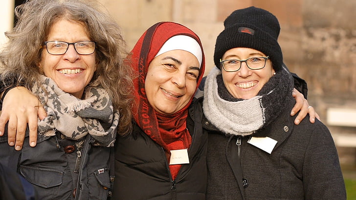 three smiling women in winter tops