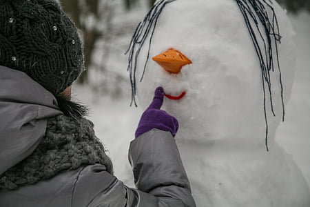 person touching snowman's lip