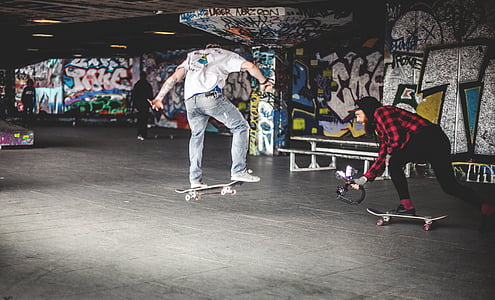 man wearing white shirt and jeans doing skateboard tricks