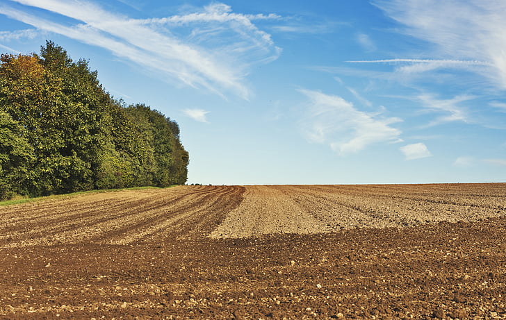 brown soil field under cloudy sky during daytime
