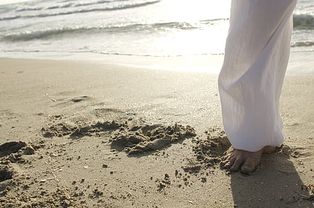 person wearing white pants standing of seashore
