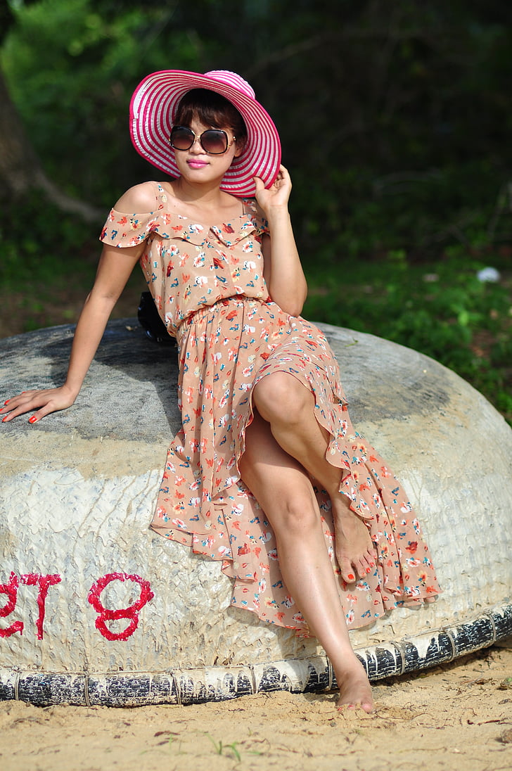 woman in brown floral dress leaning on brown rock posing for photoshoot
