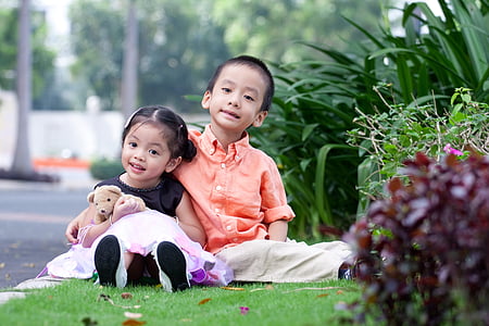 boy sitting beside smiling girl on grass lawn