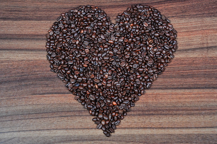 coffee beans in heart formation on brown wooden table