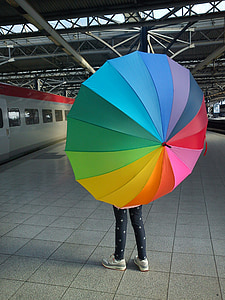 person standing while holding rainbow umbrella