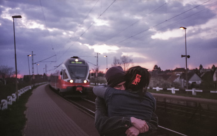 two persons hugging each other on train station platform