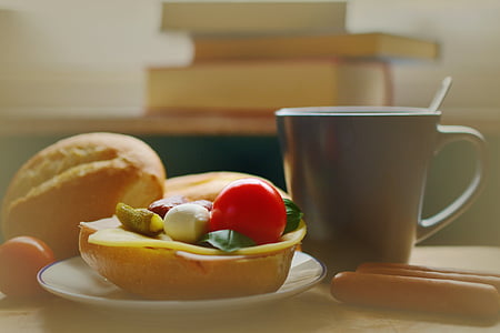 baked bread placed on white ceramic saucer near black ceramic mug placed on brown wooden table