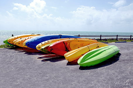 aligned assorted-color kayaks on gray seashore during daytime photo