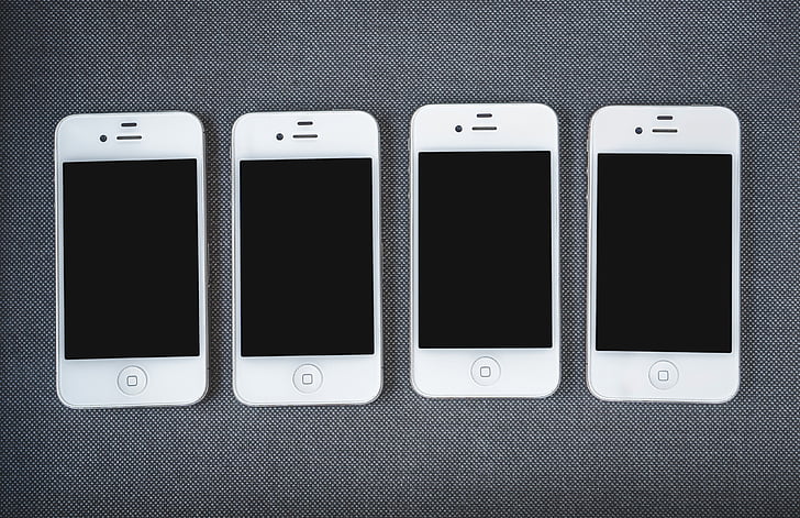 four white 4 iPhone 4's on gray textile