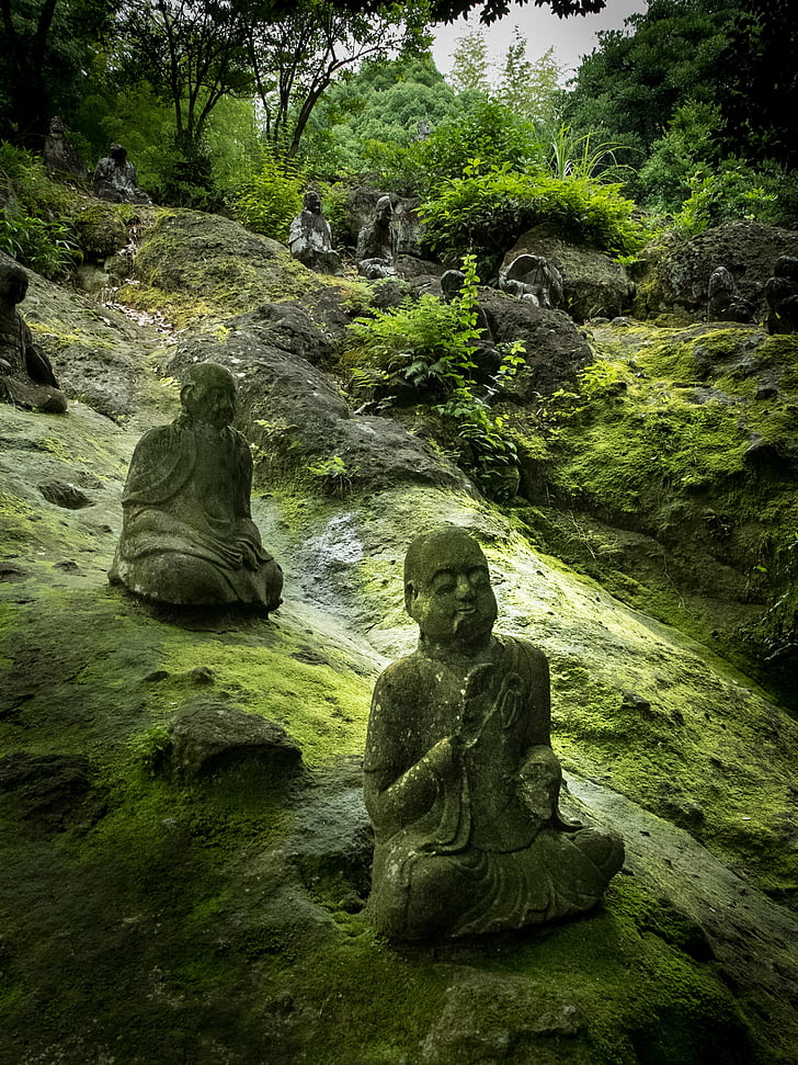three Buddha figurines on rock