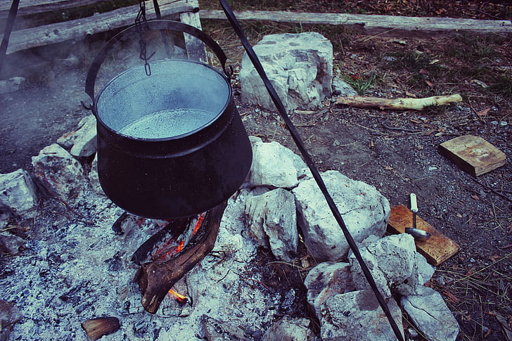black cooking pot above firewoods
