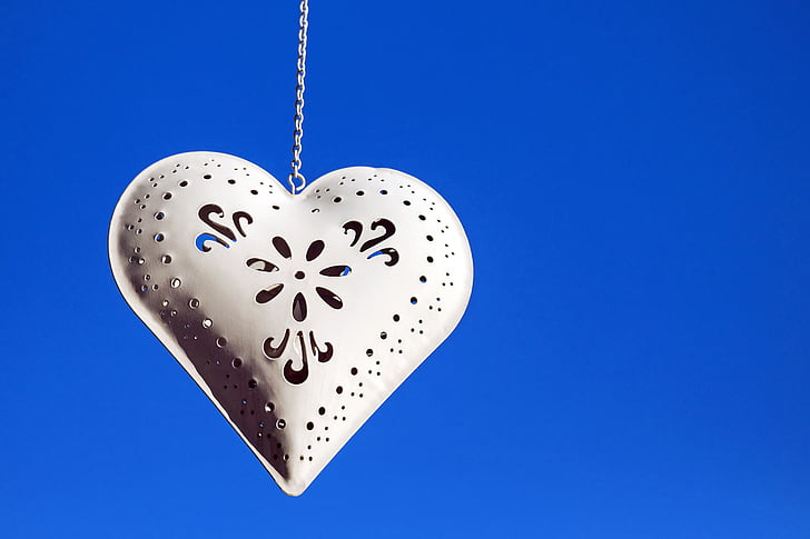 silver-colored heart pendant with chain necklace and blue background