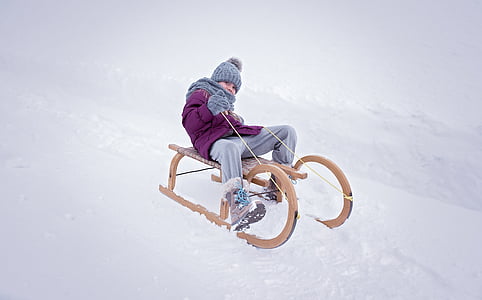 boy riding brown sled