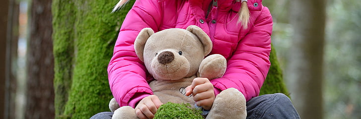 shallow focus photography of person holding bear plush toy