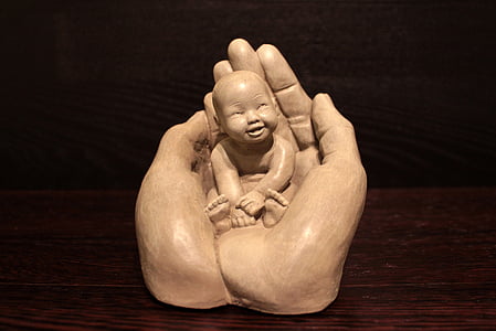 baby on human hand figurine