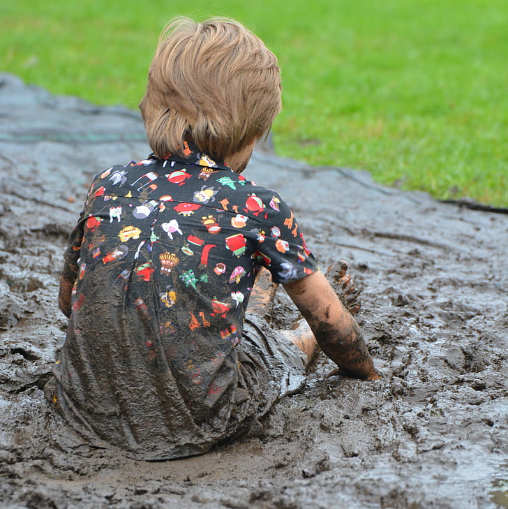 person wearing multicolored shirt while sitting on brown mud