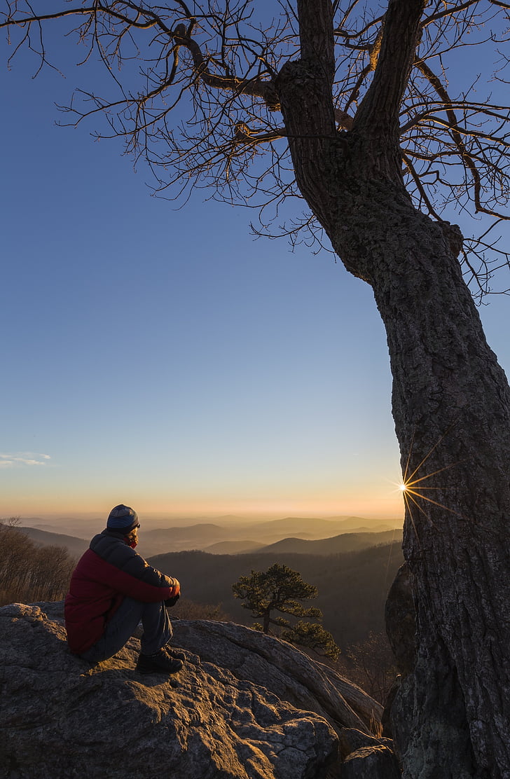 Royalty-Free photo: Man sitting on rock watching sunrise