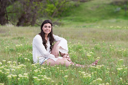 woman in white top sitting on grass during daytime