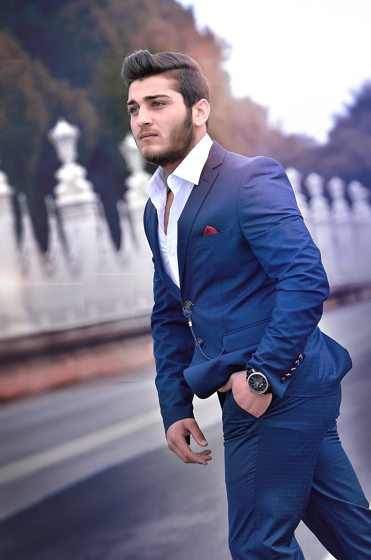 man wearing blue suit jacket and dress pants standing near road