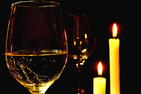 two wine glasses beside two taper candles
