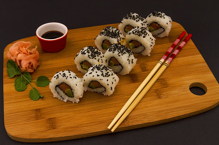 white sushi roll on brown wooden chopping board