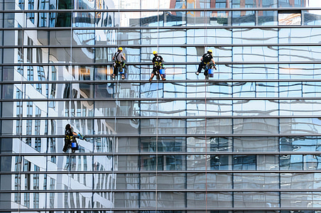four people cleaning glass walls