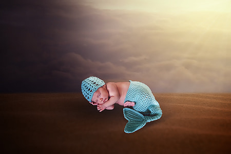 baby in teal knit cap and mermaid tail bottoms