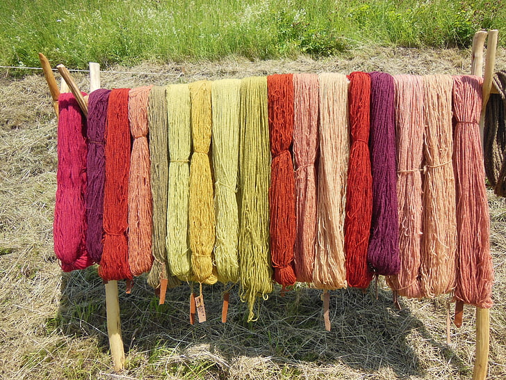 assorted-color thread hanging on wooden rack