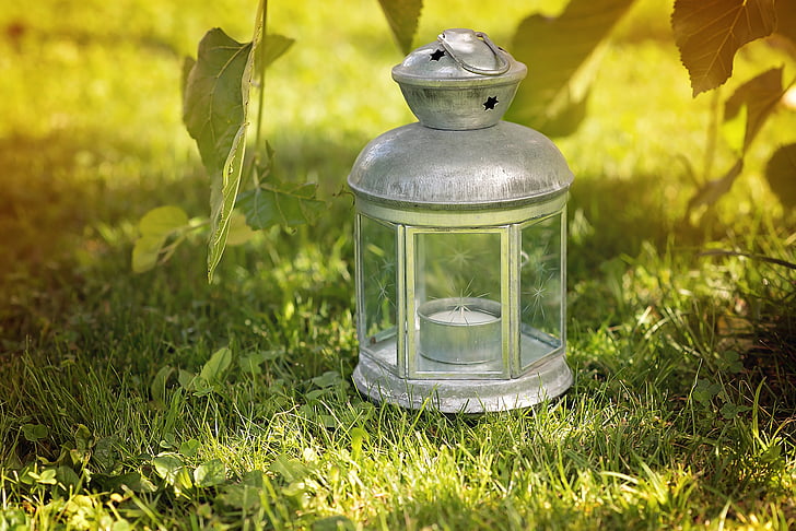 grey candle lantern on green grass field