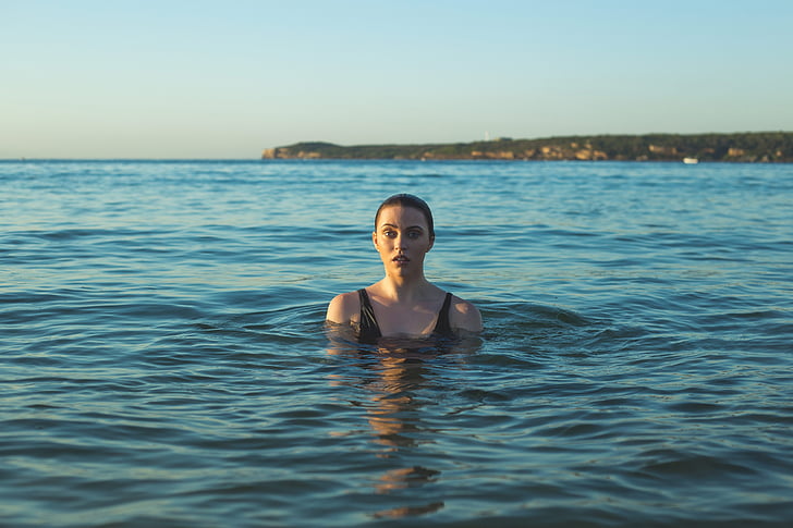 woman wearing black tank top swimming on sea at daytime