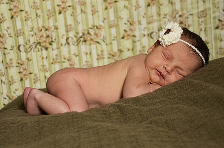 baby lying on brown textile