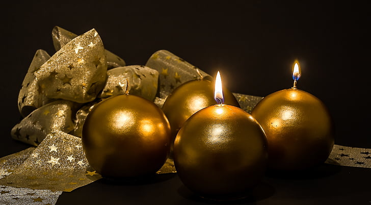 four gold-colored candles beside brown textile