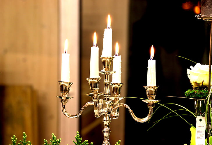 five white lighted candles on brown holder