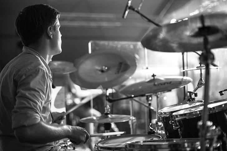 grayscale photography of man wearing collared shirt playing drum