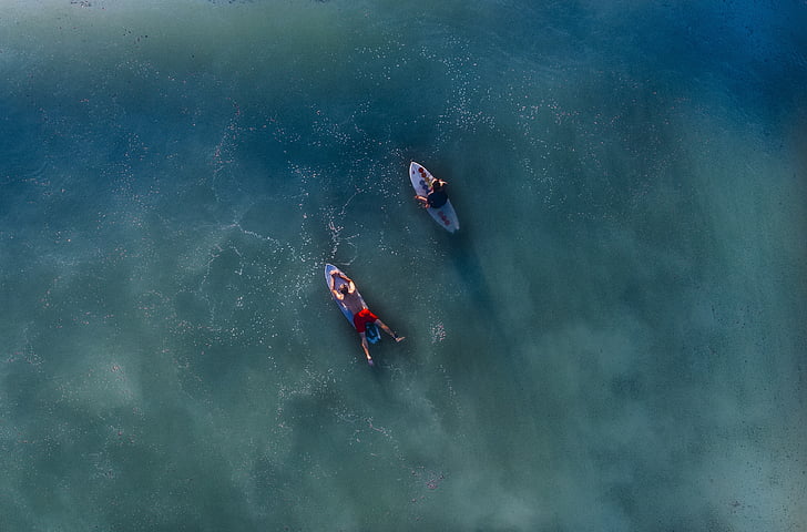aerial photography of two male riding surfboards