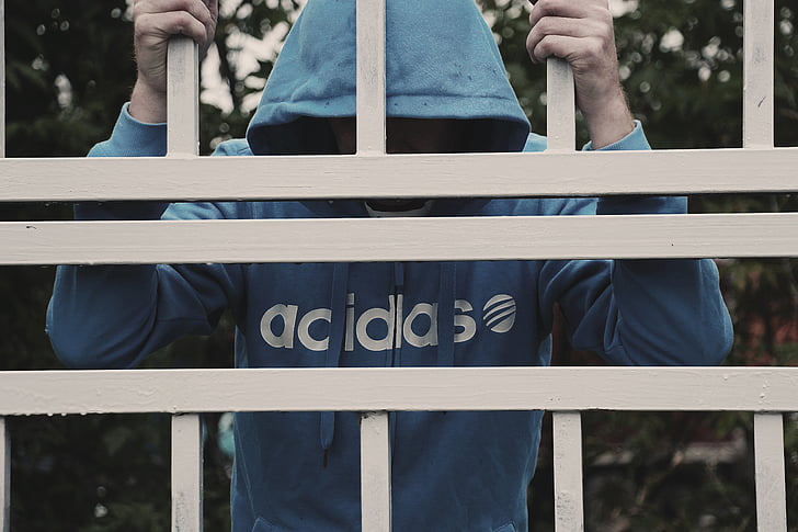 person in blue adidas shirt holding gate bars