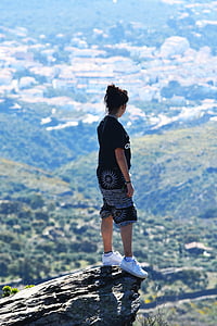 black haired woman in black top and shorts on mountain cliff during day time