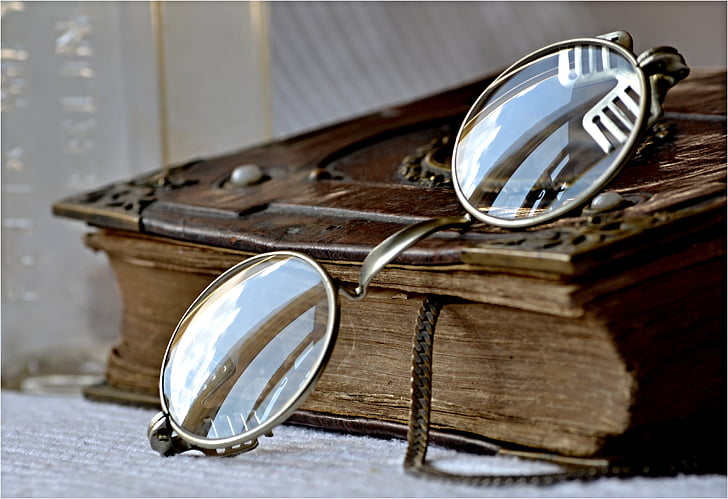 close-up photography of gold-colored frame eyeglasses on top of brown book