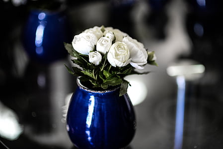 white rose flowers with blue glass vase