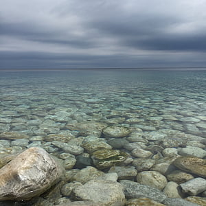 calm body of ocean with stones at daytime