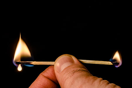 person holding two lighted safety matches sticks