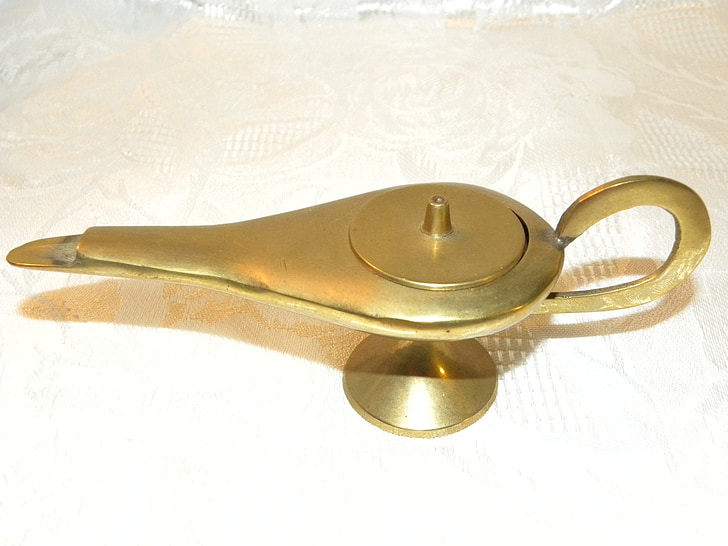 brass-colored oil lamp on white textile