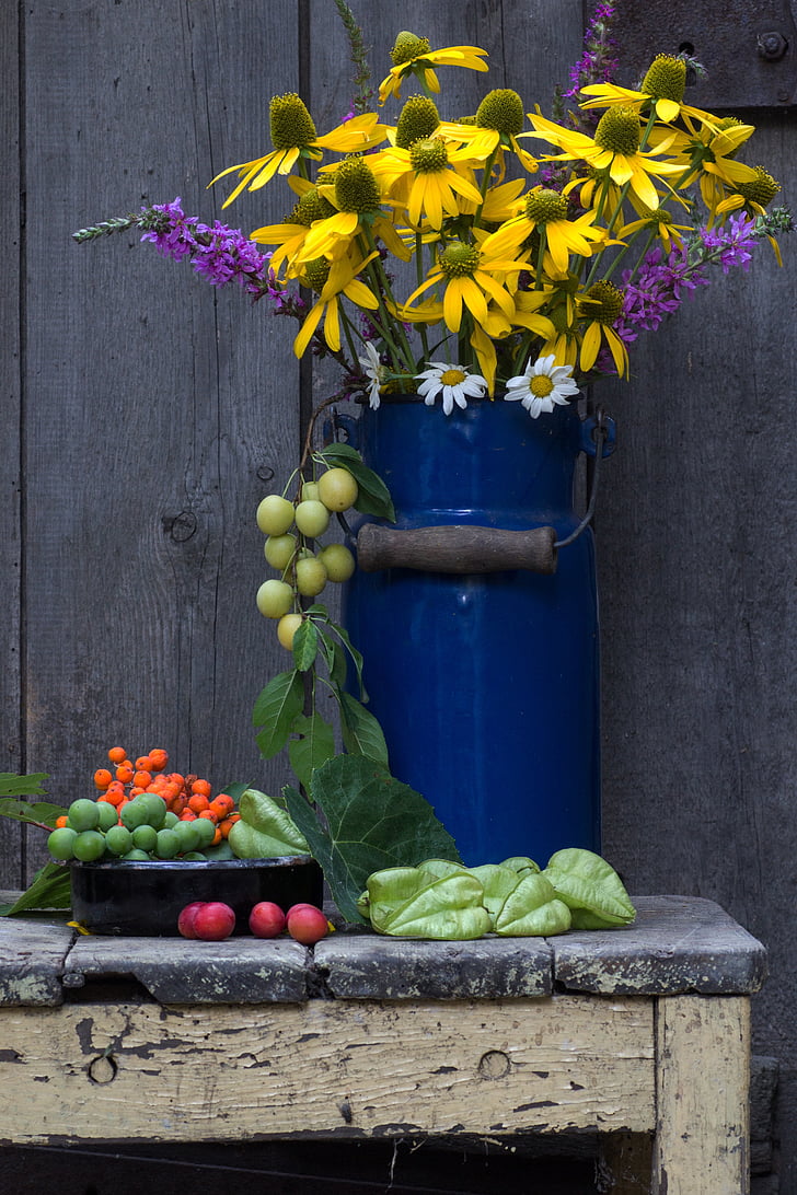 photography of yellow flowers in blue metal vase