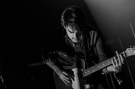 grayscale photo of man holding guitar