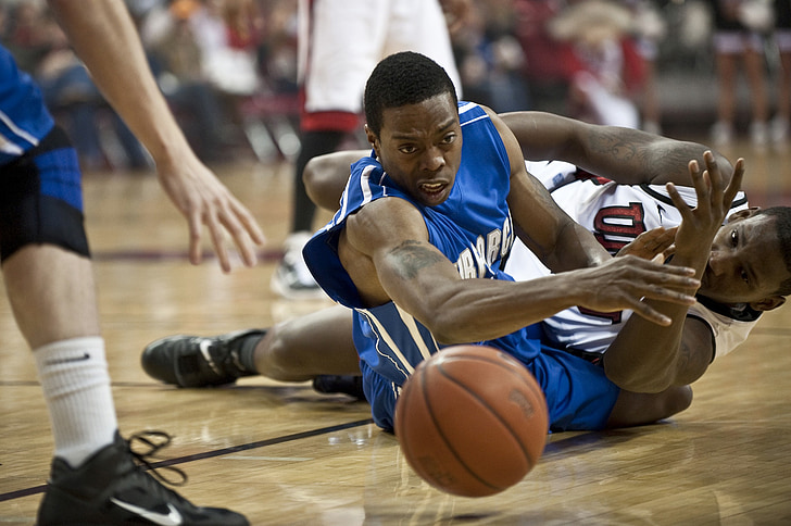 two basketball player on the ground looking at basketball