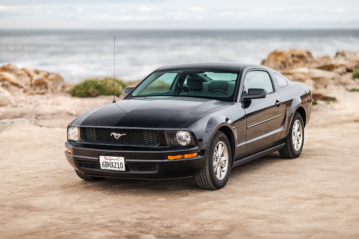 black Ford Mustang coupe beside body of water