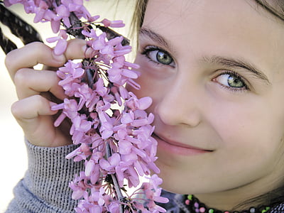 close-up photography of girl holding pink flowers