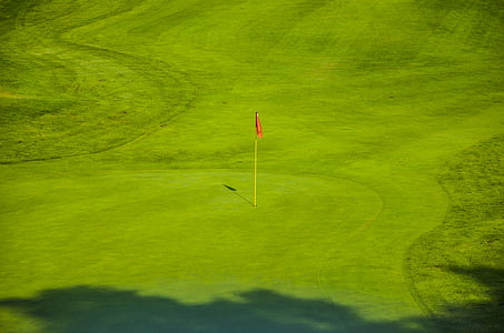 red flag on green golf course during day