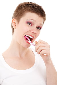 woman using white and pink toothbrush