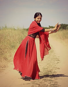 woman wearing red and black floral sari dress standing on brown sand during daytime